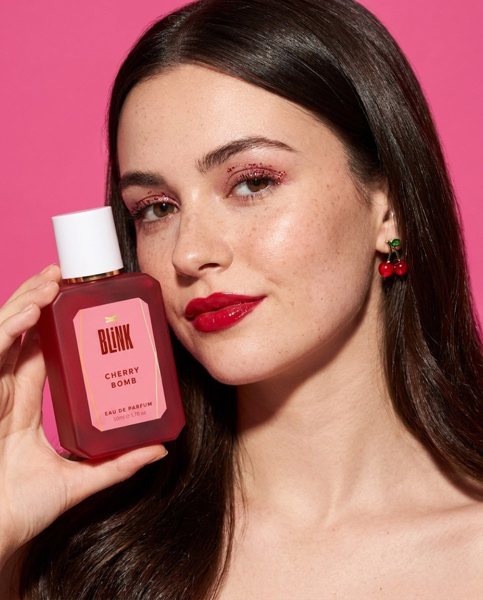 Tânără cu parfumul BLINK Cherry Bomb lângă obraz, pe fundal roz